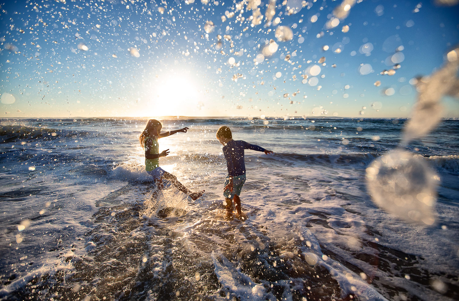 a silhouette of a brother and sister playing in the surf on the gold coast for RACQ